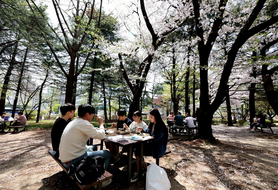 People eat lunch outdoors in Yeouido, western Seoul, without wearing masks. From Monday, Korea will end its outdoor mask mandate. [KIM SANG-SEON] 