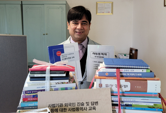 Yang Mo-min, 49, at his office in Dobong District, northern Seoul, with books he studies on April 16. [HAM MIN-JUNG]