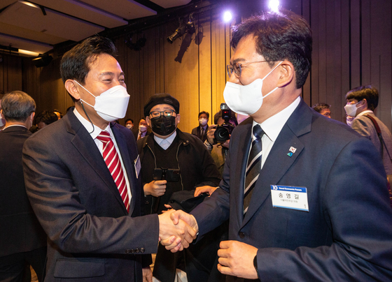Seoul Mayor Oh Se-hoon, left, shakes hands with former Democratic Party (DP) Chairman Song Young-gil at a forum in Seoul last month. The two will face off against each other for the Seoul mayoral post in the June 1 local elections. [NEWS1]