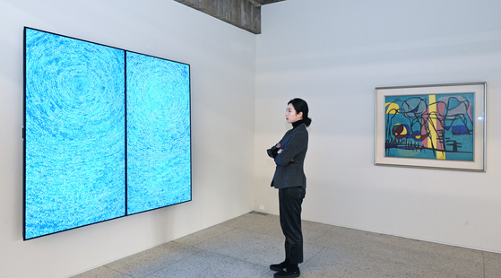 A model looks at a digital version of ″05-IV-71 #200 (Universe)″ by Kim Whanki (1913-1974) on an LG OLED display at Gana Art Bogwang in Yongsan, central Seoul. [LG ELECTRONICS]