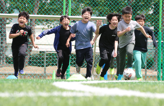Students play football without masks at an elementary school in Daejeon on Monday following the end of the outdoor mask mandate. [NEWS1]