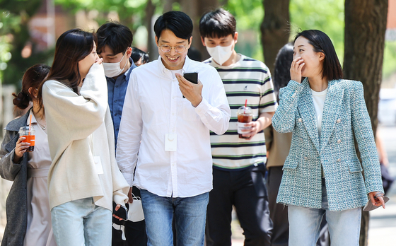 A group of people take a walk without masks on Monday, the first day the outdoor mask mandate was lifted. [YONHAP]