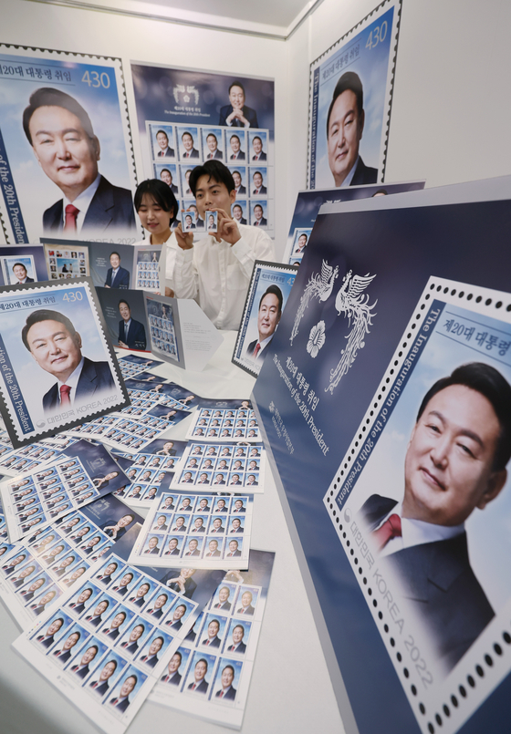 Korea Post employees pose with stamps of President-elect Yoon Suk-yeol which were printed to commemorate the inauguration of Korea’s 20th President at the postal office’ museum in central Seoul on Tuesday. The stamps will go on sale starting May 10 when Yoon is sworn into office. [YONHAP] 