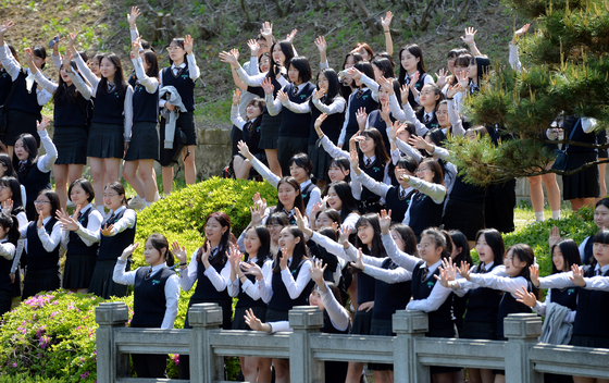 Taking off their masks, seniors from a high school have their graduation photos taken at the National Cemetery in Daejeon on Wednesday. [KIM SEONG-TAE]