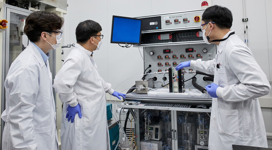 LG Chem researchers look at an electrochemical reactor that uses the carbon dioxide in the air as a raw material in the production of plastics. [LG CHEM]