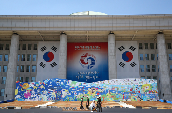 Staffers prepare the stage for incoming President Yoon Suk-yeol’s inauguration ceremony next week in front of the of the National Assembly main building in Yeouido, western Seoul, Thursday. [JOINT PRESS CORPS]