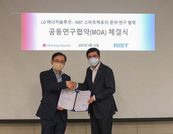 LG Energy Solution Chief Product Officer Kim Myung-hwan, left, and Nam Soo-hi, president of the Research Institute of Industrial Science and Technology, shake hands after signing an agreement on the cooperation of developing technologies for smart factory systems, at the battery maker’s plant in Ochang, North Chungcheong, Tuesday. [LG ENERGY SOLUTION]