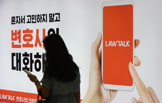 A pedestrian passes by an advert of legal service app LawTalk in southern Seoul, Aug. 5, 2021. [YONHAP]