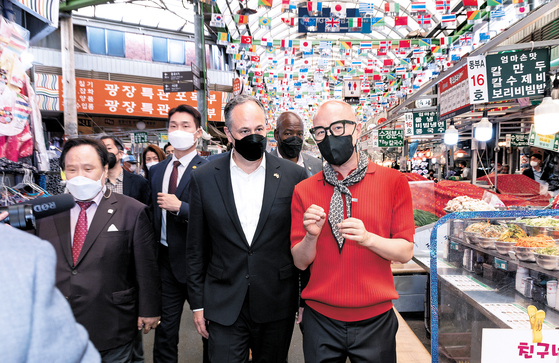 Douglas Emhoff, center, visits Gwangjang Market in Seoul with television personality Hong Seok-cheon, right, on Wednesday. [KIM HYUN-DONG]