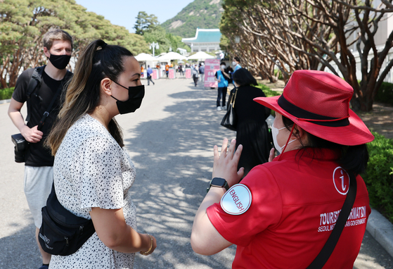 A tour guide explains about the Blue House to foreign visitors taking a look around the former presidential complex in Jongno District, central Seoul, on Wednesday, the second day it was open to the public. [YONHAP]