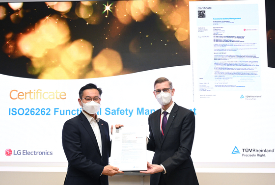 Kim Jin-kyung, head of the LG Electronics SIC Center, poses with Frank Juettner, head of German testing provider TÜV Rheinland, after receiving a certificate certifying the safety of the company's auto chip design processes. [LG ELECTRONICS]