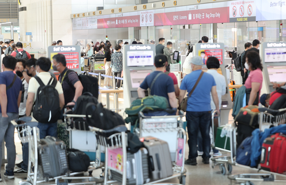Travelers wait in line at Incheon International Airport on Sunday. [YONHAP]