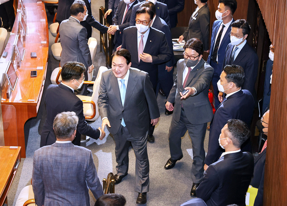 President Yoon Suk-yeol, center, shakes hands with rival Democratic Party lawmakers after his first parliamentary address at the National Assembly in Yeouido, western Seoul, Monday morning. [KIM SEONG-RYONG]