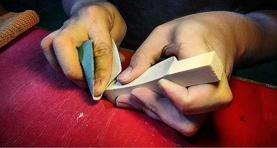 A craftsman shapes a piece of wood to make a leg of a soban. [YANGVAN]