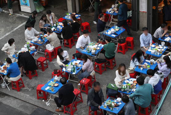 People drink beer outside a pub at Euljiro, central Seoul, on May 11. [NEWS1]