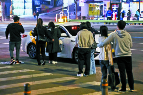 People try TO hail a taxi near Gangnam Station, Seoul, on April 18. [YONHAP]