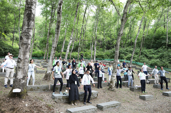 Ambassadors and diplomats try a session of meditation and stretching in an SK forest in Mount Indeung. [PARK SANG-MOON]