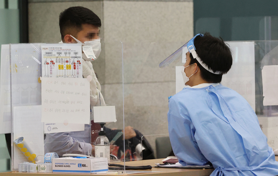 A traveler talks with a quarantine official at the arrival area of Incheon International Airport on Tuesday. Health authorities said they will boost monitoring to prevent monkeypox cases coming in. [YONHAP]