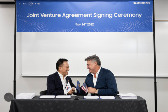 Choi Yoon-ho, left, CEO of Samsung SDI, and Mark Stewart, COO at Stellantis North America, shake hands after signing an agreement to invest $2.5 billion to build an EV battery factory in Kokomo, Indiana. [SAMSUNG SDI] 