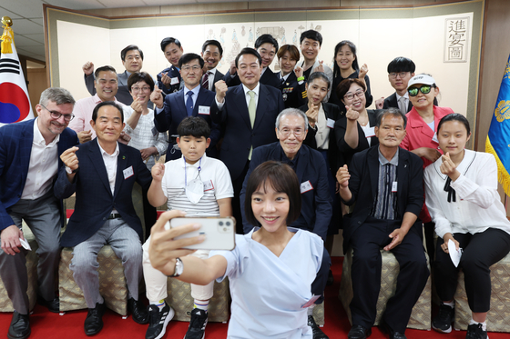 President Yoon Suk-yeol poses for a commemorative photo after a luncheon at the presidential office in Yongsan, Seoul, on Wednesday, with Kim Na-yun, center front, who won four gold medals at the WBC Fitness World Body Classic, and other representatives selected for giving hope to the nation. The guests were all present at Yoon's inauguration ceremony on May 10, and received a special watch at the luncheon. [NEWS1]