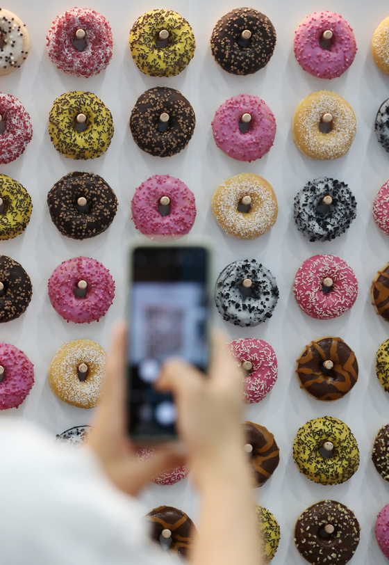 A visitor takes a photo of various types of donuts displayed at the 2022 Suwon Cafe & Bakery Fair on Thursday, held at the Suwon Convention Center in Gyeonggi. [NEWS1]