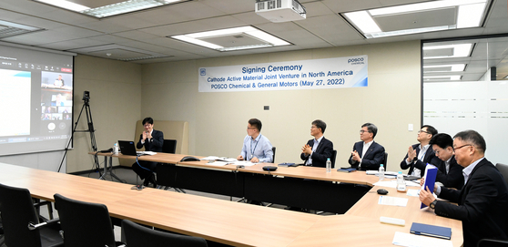 Min Kyung-zoon, far right, CEO of Posco Chemical, and Doug Parks, vice president at General Motors' Global Product Development, sign an agreement to establish a joint cathode materials plant in Canada via video call Friday. [POSCO CHEMICAL]