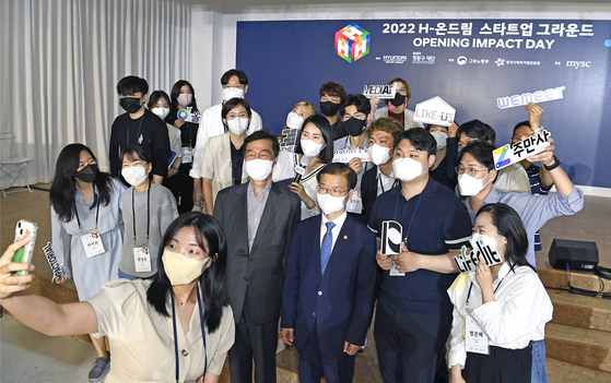 Kwon O-kyu, left, chairperson of Hyundai Motor Chung Mong-Koo Foundation, and Employment and Labor Minister Lee Jeong-sik, right, pose for a photo with participants of H-OnDream Opening Impact Day on Monday. [HYUNDAI MOTOR]