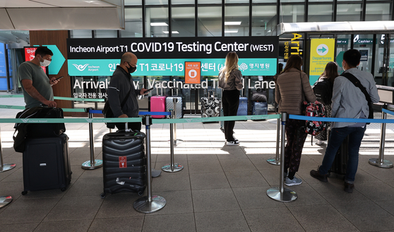 Inbound tourists receive tests at a Covid-19 testing station at Incheon International Airport on Wednesday, when the number of tests required after entering the country was reduced from two to one. [YONHAP]