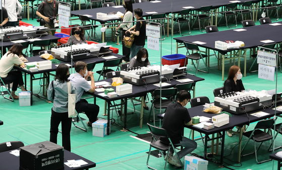 Election commission staffers check tallying devices at the Seoul National University Gymnasium in Gwanak District, southern Seoul, Tuesday, on the eve of the June 1 local elections. [NEWS1]