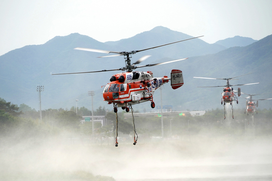 Helicopters collect water from a river in Miryang Wednesday to put out a blaze in the city. [NEWS1]