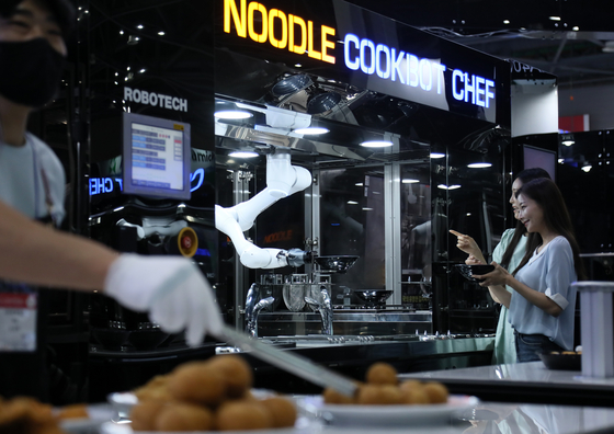 A robotic arm makes a noodle dish during a demonstration exhibited at Seoul Food & Hotel 2022, the biggest food and hospitality exhibition in the country, held Tuesday at Kintex in Goyang, Gyeonggi. This year some 962 companies from 30 countries are participating in the exhibition organized by the Korea Trade-investment Promotion Agency. The exhibition runs through June 10. [YONHAP]