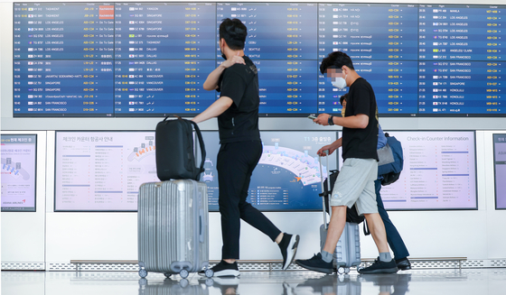 Travelers view the flight information display screen in the departure hall of Incheon International Airport Terminal 1 Wednesday afternoon following the normalization of international flights. Starting midnight, major restrictions were lifted on arriving flights. [YONHAP]