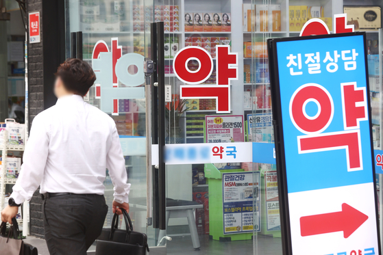 A pedestrian walks past a pharmacy in Seoul on Wednesday. Pharmaceutical companies are raising the sticker prices of over-the-counter drugs due to rising inflation. Prices of Ildong Pharmaceutical's Aronamin C Plus vitamins and GC Biopharma's Zenol Cool medical patches are expected to rise 10 percent within the latter half of this year. [YONHAP]