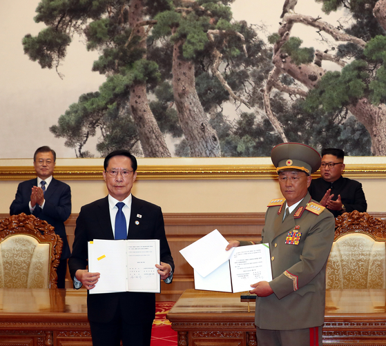 With former President Moon Jae-in (far left) and North Korean leader Kim Jong-un (far right) looking on, South Korean Defense Minister Song Young-moo (center-left) and North Korean Minister of the People's Armed Forces No Kwang-chol (center-right) hold up copies of the Inter-Korean Military Agreement on Sept. 19, 2018. [JOINT PRESS CORPS]