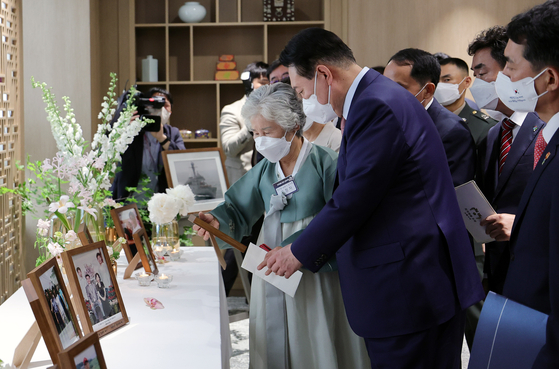 President Yoon Suk-yeol, right, welcomes a group of battle survivors and relatives of fallen soldiers to the presidential office on Thursday. Twenty people, including survivors of North Korea's torpedo attack on a South Korean warship in 2010, were invited to lunch with the president. [NEWS1]