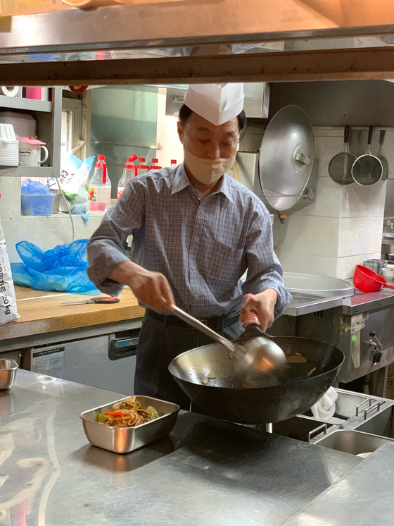 A cook at Chwihong, a Chinese restaurant in Gangnam, puts food in a reusable container for delivery. [SEO JI-EUN]