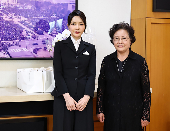 First lady Kim Keon-hee, left, poses for a commemorative photo with Kwon Yang-sook, wife of the late President Roh Moo-hyun, at her home in Bongha Village, Gimhae, in South Gyeongsang on Monday. [YONHAP]