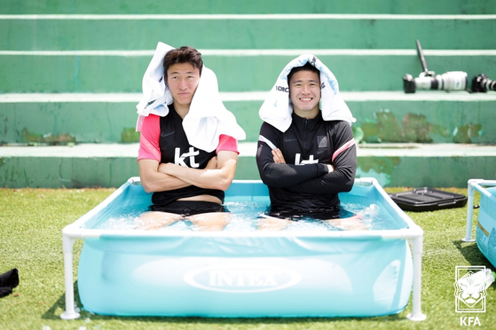 Hwang Ui-jo, left, and Kwon Chang-hoon take an ice bath at the side of the pitch during a national team friendly at the National Football Center in Paju, Gyeonggi on Sunday. Korea will take on Egypt in the final of four June friendlies on Tuesday. [YONHAP]