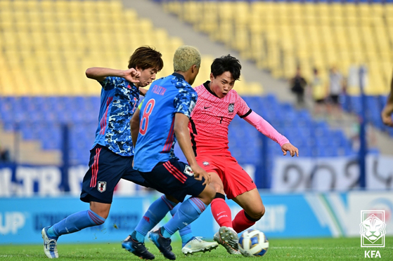 Korea's Cho Young-wook, right, dribbles past two Japanese players in the quarterfinals of the U-23 Asian Cup at Pakhtakor Central Stadium in Tashkent, Uzbekistan on Sunday. [NEWS1]