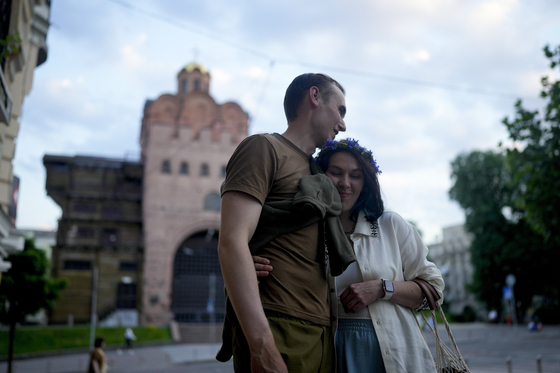 Stand-up comics Serhiy Lipko and Anastasia Zukhvala embrace during an interview with the Associated Press on their wedding day in Kyiv, Ukraine, on Saturday, June 11. Lipko and Zukhvala are among those using humor as a weapon, and to keep spirits up. But he'll soon have a real weapon in his hands, because he's going into battle. [AP]