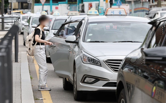 A customer gets in a taxi at Seoul Station on Tuesday. Starting Wednesday, cab hailing platforms including Kakao Taxi will be allowed to provide taxi sharing services. The companies must provide information on the destination and the time during which passengers will be sharing the ride. The app must have a function where the passenger can immediate contact the police or customer service in case of an emergency. Excluding van-type taxis, only passengers of the same gender are allowed to share a cab. Cab sharing has been legally banned since 1982. [YONHAP]