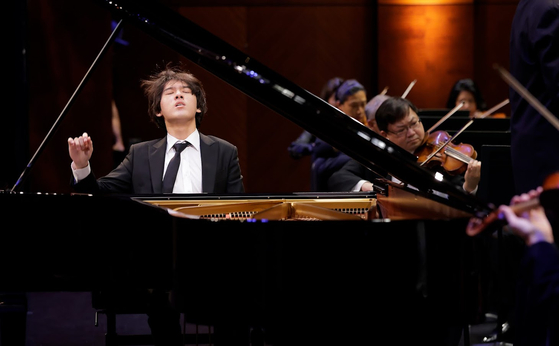 Yunchan Lim from Korea performs a Mozart Concerto with conductor Nicholas McGegan and the Fort Worth Symphony Orchestra in the Semifinal round in the Sixteenth Cliburn International Piano Competition in Bass Performance Hall in Fort Worth, Texas, on June 11. [RALPH LAUER] 