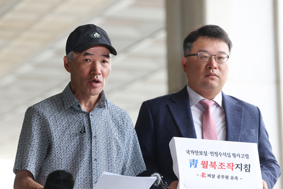 Lee Rae-jin, left, brother of murdered South Korean official Lee Dae-joon, talks to reporters outside the Seoul Central District Prosecutors' Office after submitting criminal complaints against three officials of Moon Jae-in administration for allegedly directing a cover-up of his brother's death in 2020. Standing next to him is the family's attorney, Kim Ki-yoon. [YONHAP]