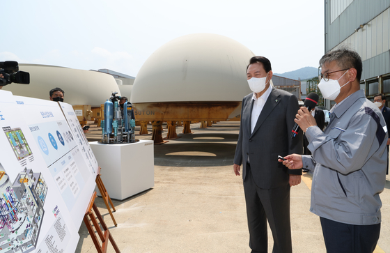 President Yoon Suk-yeol gets a briefing on Korea's ARP1400 nuclear reactor at Doosan Enerbility in Changwon, South Gyeongsang on Wednesday. [YONHAP] 