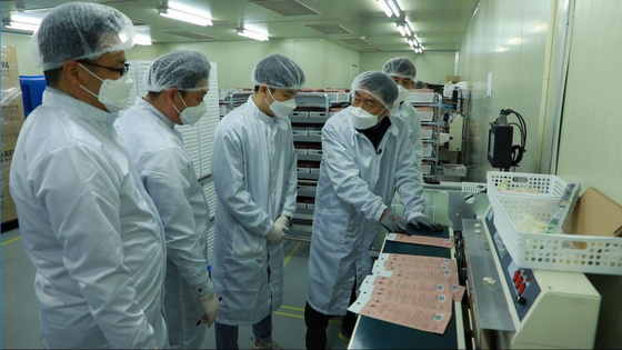 An engineer from Samsung Electronics instructs workers at a local facial mask manufacturer on how to improve production capacity. [YONHAP] 