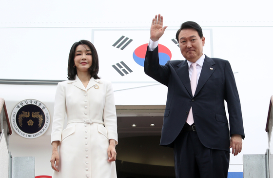 President Yoon Suk-yeol waves from the gangway to Air Force One at Seoul Air Base in Seongnam, just south of Seoul, ahead of his departure to Madrid to attend the NATO summit on Monday. First lady Kim Keon-hee stands next to him. [YONHAP]