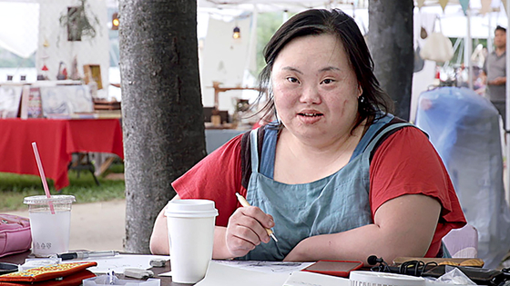 A scene from the documentary "Please Make Me Look Pretty," which shows how Jung Eun-hye developed as a hit caricature artist. Her stepfather Seo Dong-il directed the film and her mother, Jang Che Hyun-sil, participated in producing. [JIN JIN PICTURES]