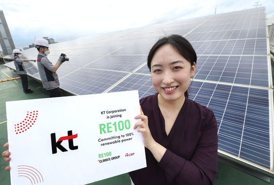 A KT employee poses for a photo in front of solar panels installed at the company's office building in Gwanak District, southern Seoul. [KT] 