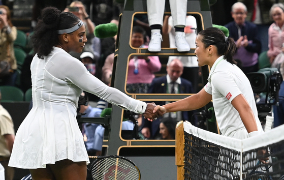 Harmony Tan of France, right, shakes hands at the net with Serena Williams of the United States after winning their women's first round match at Wimbledon at the All England Lawn Tennis and Croquet Club in London on Tuesday. [EPA/YONHAP]