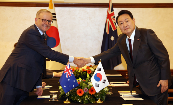 Korean President Yoon Suk-yeol, right, shakes hands with Australian Prime Minister Anthony Albanese in a hotel in Madrid on Tuesday. [YONHAP]